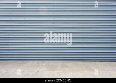 Oberfläche der Fassade des Fabrikgebäudes aus grauem Wellblech mit Betonboden. Stockfoto