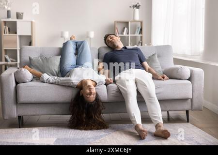 Schlafendes junges Paar, das kopfüber auf dem Sofa liegt Stockfoto