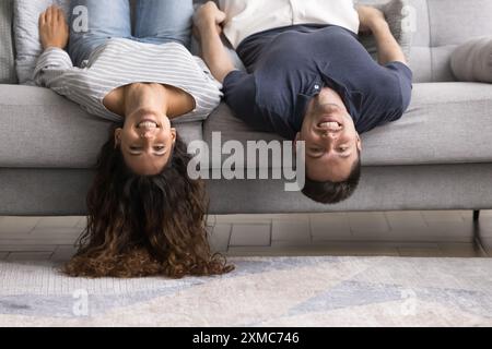 Fröhliches Paar mit verspielter Stimmung, das kopfüber auf dem Sofa liegt Stockfoto