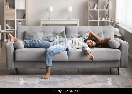 Frau, die sich in entspannter Position auf dem Sofa ausbreitet Stockfoto