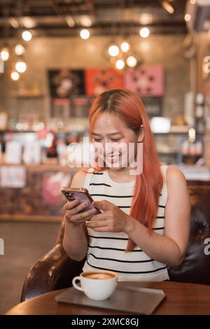 Porträt der schönen glücklichen asiatischen Frau, die Handy im Coffee Shop benutzt Stockfoto