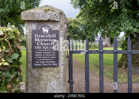 Gracehill, Nordirland - 26. Juli 2024: Historische mährische Siedlung wird zum UNESCO-Weltkulturerbe erklärt. Schild an den Eingangstoren zum Sqaure. Stockfoto