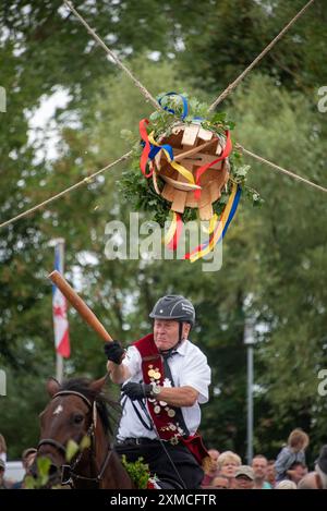 Klockenhagen, Deutschland. Juli 2024. Ein Reiter schlägt eine Heringsboje mit einem Schläger. Er konkurriert mit 15 weiteren Fahrern um mehrere Königstitel beim traditionellen Fassschlagen in Klockenhagen. 2017 wurde die weit verbreitete Praxis des Fass-Schlagens auf der Ostsee in die Liste des immateriellen Kulturerbes der UNESCO aufgenommen. Quelle: Stephan Schulz/dpa/Alamy Live News Stockfoto