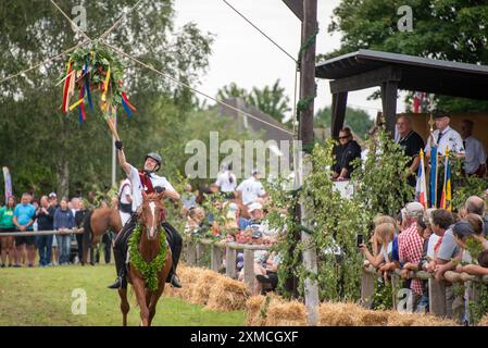 Klockenhagen, Deutschland. Juli 2024. Ein Reiter schlägt eine Heringsboje mit einem Schläger. Er konkurriert mit 15 weiteren Fahrern um mehrere Königstitel beim traditionellen Fassschlagen in Klockenhagen. 2017 wurde die weit verbreitete Praxis des Fass-Schlagens auf der Ostsee in die Liste des immateriellen Kulturerbes der UNESCO aufgenommen. Quelle: Stephan Schulz/dpa/Alamy Live News Stockfoto