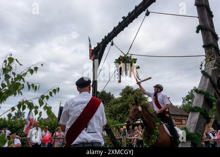 Klockenhagen, Deutschland. Juli 2024. Ein Reiter schlägt eine Heringsboje mit einem Schläger. Er konkurriert mit 15 weiteren Fahrern um mehrere Königstitel beim traditionellen Fassschlagen in Klockenhagen. 2017 wurde die weit verbreitete Praxis des Fass-Schlagens auf der Ostsee in die Liste des immateriellen Kulturerbes der UNESCO aufgenommen. Quelle: Stephan Schulz/dpa/Alamy Live News Stockfoto