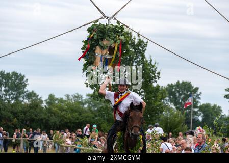 Klockenhagen, Deutschland. Juli 2024. Ein Reiter schlägt eine Heringsboje mit einem Schläger. Er konkurriert mit 15 weiteren Fahrern um mehrere Königstitel beim traditionellen Fassschlagen in Klockenhagen. 2017 wurde die weit verbreitete Praxis des Fass-Schlagens auf der Ostsee in die Liste des immateriellen Kulturerbes der UNESCO aufgenommen. Quelle: Stephan Schulz/dpa/Alamy Live News Stockfoto