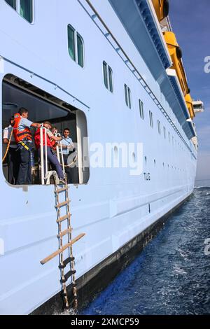 Nizza, Frankreich: Hafenpilotenboot nähert sich der riesigen MEERESHYMNE der Royal Caribbean, um in Villefranche sur Mer von Bord zu gehen. Ein einzigartiger Zwischenstopp für das größte Kreuzfahrtschiff dieses Jahr im kleinen Hafen der französischen Riviera. Nach der Sommersaison sollte das beeindruckende Schiff im Rahmen einer Umschichtung von Europa nach Singapur durch den Suez-Kanal segeln, aber nach Spannungen am Roten Meer und Drohungen mit Houthi-Raketen auf Schiffe, stattdessen wird sie ohne Passagier die Südspitze Afrikas erkunden, um Dubai und Asien zu erreichen. Quelle: Kevin Izorce/Alamy Live News Stockfoto