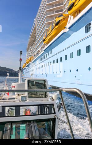 Nizza, Frankreich: Hafenpilotenboot nähert sich der riesigen MEERESHYMNE der Royal Caribbean, um in Villefranche sur Mer von Bord zu gehen. Ein einzigartiger Zwischenstopp für das größte Kreuzfahrtschiff dieses Jahr im kleinen Hafen der französischen Riviera. Nach der Sommersaison sollte das beeindruckende Schiff im Rahmen einer Umschichtung von Europa nach Singapur durch den Suez-Kanal segeln, aber nach Spannungen am Roten Meer und Drohungen mit Houthi-Raketen auf Schiffe, stattdessen wird sie ohne Passagier die Südspitze Afrikas erkunden, um Dubai und Asien zu erreichen. Quelle: Kevin Izorce/Alamy Live News Stockfoto