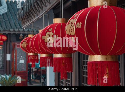 Suzhou, China - 01. Januar 2019: Leuchtende rote Laternen hängen während der Festivalsaison elegant unter einem traditionellen Dach im chinesischen Innenhof Stockfoto