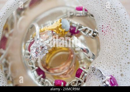 Reinigung Vintage Schmuck Diamant Ring und Armband in Glas auf Holztischhintergrund Stockfoto