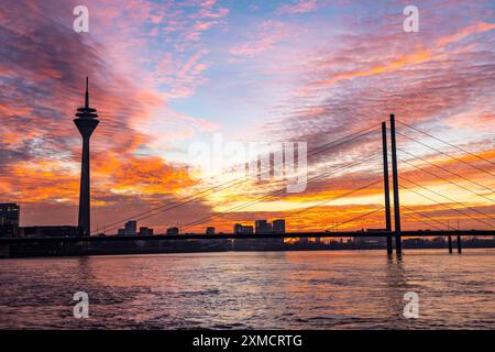 Wintersonnenuntergang am Rhein bei Düsseldorf, Rheinturm, Frachtschiff, Rheinkniebrücke, Nordrhein-Westfalen, Deutschland Stockfoto