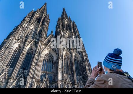 Kölner Dom, Blick auf die Westfassade, am Nordturm, Tourist macht ein Foto mit Handy, Köln, Deutschland Stockfoto