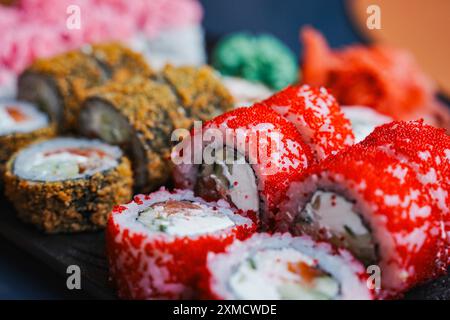 Japanisches Essen: Sushi und verschiedene Brötchen auf einem schwarzen Teller. Japanisches Restaurantmenü, Sushi-Lieferung. Ausgewählter Fokus. Hochwertige Fotos Stockfoto