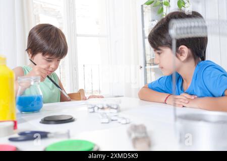 Ein Kind malt ein Handwerk, während sein Bruder ihn beobachtet. Freizeit und Kreativität. Stockfoto