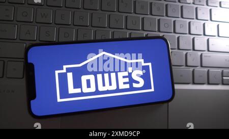 In dieser Fotoabbildung wird Lowes Logo auf einem Smartphone mit Hintergrund einer Laptop-Tastatur angezeigt. Stockfoto