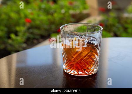 Ein Glas Whiskey mit einer Kirsche oben und einer Orangenscheibe innen. Das Getränk ist ein traditionelles altmodisches manhattan. Stockfoto