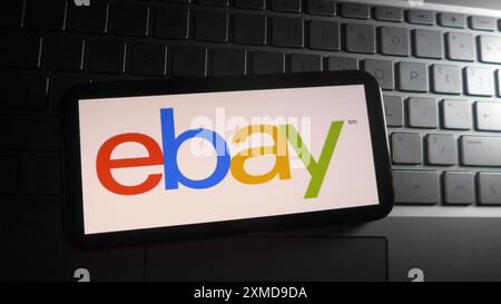 In dieser Fotoabbildung wird das ebay-Logo auf einem Smartphone mit Hintergrund einer Laptop-Tastatur angezeigt. Stockfoto