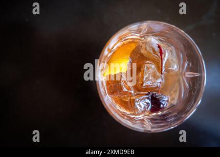 Ein Glas Whiskey mit einer Kirsche oben und einer Orangenscheibe innen. Das Getränk ist ein traditionelles altmodisches manhattan. Stockfoto