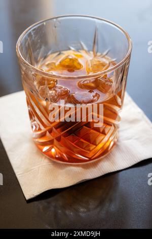 Ein Glas Whiskey mit einer Kirsche oben und einer Orangenscheibe innen. Das Getränk ist ein traditionelles altmodisches manhattan. Stockfoto