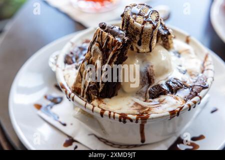 Ein Dessert mit Schokolade und Marshmallows auf einer Schüssel Eis. Das Dessert wird auf einem weißen Teller serviert und mit Schokoladensauce belegt Stockfoto