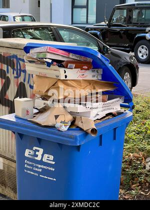 Überlaufender Papierkorb, auf einem Bürgersteig stehend, wartet darauf, von einer kommunalen Abfallentsorgungsfirma entleert zu werden, Recycling Stockfoto