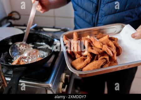 Die Hände eines nicht erkennbaren lateinischen Mannes frittieren chilenisches süßes gebratenes Gebäck Calzones Rotos in einer Pfanne in ihrer Küche Stockfoto