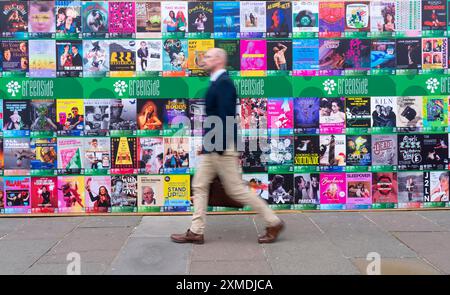 Man spaziert an Plakaten mit vielen Plakaten vorbei, die auf dem Fringe Festival in Edinburgh, Schottland, Großbritannien, gezeigt werden Stockfoto