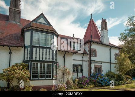 Port Sunlight, Wirral, Großbritannien - 26. Juli 2024 - Haus mit spitzem Dach schwarz-weiß mit Blumen im Garten Stockfoto