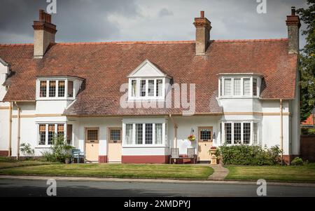 Port Sunlight, Wirral, Großbritannien - 26. Juli 2024 - Reihe von 3 Reihenhäusern mit cremefarbenen Türen und schrägem rotem Ziegeldach Stockfoto