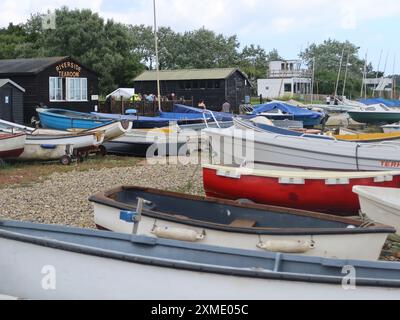 Blick auf den Riverside Tearoom in einer traditionellen schwarzen Suffolk Hütte, neben den Booten und Jollen, die auf dem Schindel am Orford Quay, Woodbridge, liegen. Stockfoto