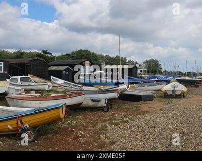 Blick auf den Riverside Tearoom in einer traditionellen schwarzen Suffolk Hütte, neben den Booten und Jollen, die auf dem Schindel am Orford Quay, Woodbridge, liegen. Stockfoto