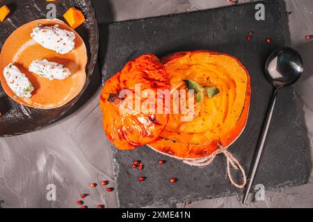 Traditionelle Gemüsesuppe, Kürbis- und Karottenpüree in einer gebackenen Kürbisschale auf einer schwarzen Glimmerplatte und Quark Quenelles mit Paprika und Kräutern Stockfoto