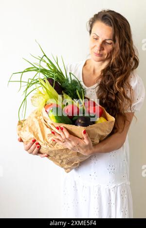 Schuss der Frau, die einen Papierbeutel mit frischen Kräutern und Gemüse hält Stockfoto