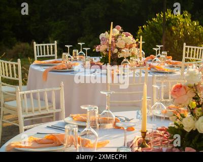 Wunderschöne Hochzeitsdekoration im Freien in der Stadt. Kerzen und getrocknete Blumen und Accessoires mit Blumenstraußen und Gläsern auf dem Tisch mit Leinentischdecken Stockfoto