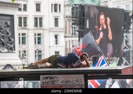 London, Großbritannien. Juli 2024. Ein Tommy-Robinson-Unterstützer, der auf einer Bushaltestelle gesehen wurde, als er an der Rallye am Trafalgar Square teilnahm. Anhänger des ehemaligen EDL-Führers und Gründers Tommy Robinson, echter Name Stephen Christopher Yaxley-Lennon, marschierten zum Trafalgar Square, um gegen das, was sie ein „zweistufiges Polizeisystem“ nennen, die Einwanderung und die LGBTQ-Bewegung zu demonstrieren. Eine Gegendemonstration fand auch von verschiedenen Gruppen statt. Quelle: SOPA Images Limited/Alamy Live News Stockfoto