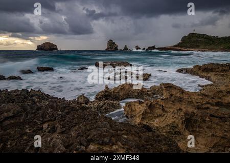 Stony Coast mit Sharp Rock Formationen in A Bay in the Sea. Regnerischer Sonnenaufgang, Dramatische Atmosphäre. Pointes Des Colibris Auf Grande Terre, Guadeloupe, Fren Stockfoto