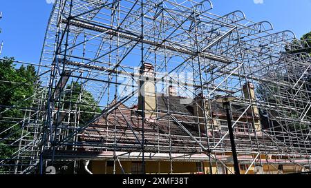 Ein Haus, das gerade renoviert wird, ist von einem weitläufigen Gerüstbau umgeben. Das Gebäude mit einem gekachelten Dach und mehreren Kaminen befindet sich in t Stockfoto