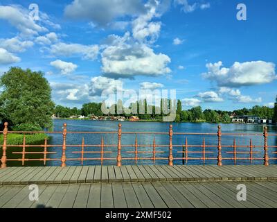 Eine Holzbrücke mit einem verzierten braunen Eisenzaun vor der Stadt mit dem Schweriner Meer in Deutschland im Sommer. Stockfoto