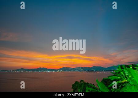 Lichtstrahlen der Sonne durchdrungen die bunten Wolken. Wunderbar die gelbe Sonne begann hinter der Insel zu erstrahlen. Das goldene Licht durchbohrte die SK Stockfoto