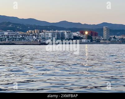 Das Punta Doncella-Licht blitzt in der Abenddämmerung über das Wasser in Estepona, Spanien. Stockfoto