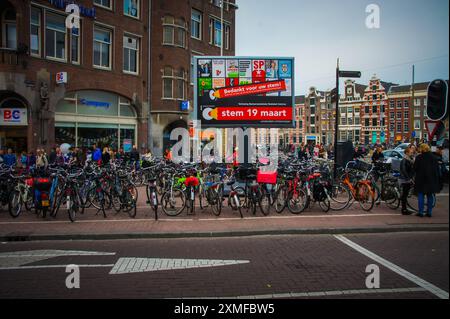 In Amsterdam schlängelt sich ein malerischer Kanal durch das historische Stadtzentrum, gesäumt von Giebelhäusern und Hausbooten. Touristen navigieren auf den Wasserstraßen auf Booten Stockfoto