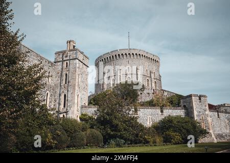 Windor Castle, Großbritannien - 16. Oktober 2023 : Blick auf eine alte Steinburg mit rundem Turm und üppig grünen Bäumen. Stockfoto