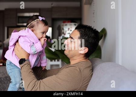 Der junge Vater trägt und lächelt mit seinem kleinen Mädchen Stockfoto