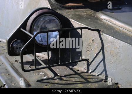 Ein Fernlicht, das bei alten gepanzerten Fahrzeugen durch einen speziellen Kühlergrill geschützt wird. Suchscheinwerfer für militärische Ausrüstung. Stockfoto