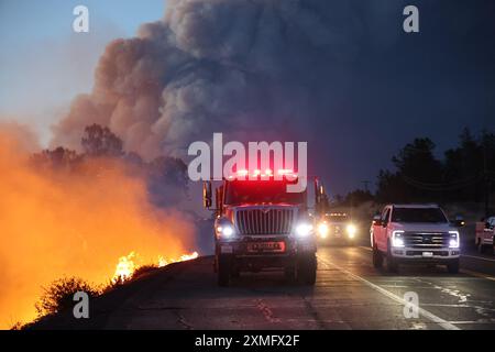 Das Foto zeigt Feuerwehrmänner, die am 25. Juli 2024 in Kalifornien, USA, gegen To Flames kämpften. Kaliforniens größtes aktives Feuer explodierte am Freitagabend, wuchs rasch unter knochentrockenen Brennstoffen an und bedrohte Tausende von Häusern, als sich die Feuerwehrleute um die Gefahr bemühten. Die Intensität und schnelle Ausbreitung des Parkfeuers veranlassten die Feuerbeamten, unwillkommene Vergleiche mit dem monströsen Lagerfeuer anzustellen, das 2018 im nahegelegenen Paradise außer Kontrolle brannte, 85 Menschen tötete und 11.000 Häuser abbrannte. Bisher wurden mehr als 130 Gebäude durch diesen Brand zerstört, und Tausende weitere sind noch immer bedroht Stockfoto