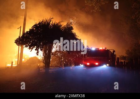 Das Foto zeigt Feuerwehrmänner, die am 26. Juli 2024 in Kalifornien, USA, gegen To Flames kämpften. Kaliforniens größtes aktives Feuer explodierte am Freitagabend, wuchs rasch unter knochentrockenen Brennstoffen an und bedrohte Tausende von Häusern, als sich die Feuerwehrleute um die Gefahr bemühten. Die Intensität und schnelle Ausbreitung des Parkfeuers veranlassten die Feuerbeamten, unwillkommene Vergleiche mit dem monströsen Lagerfeuer anzustellen, das 2018 im nahegelegenen Paradise außer Kontrolle brannte, 85 Menschen tötete und 11.000 Häuser abbrannte. Bisher wurden mehr als 130 Gebäude durch diesen Brand zerstört, und Tausende weitere sind noch immer bedroht Stockfoto