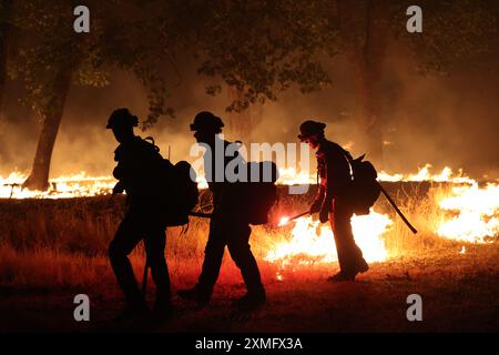 Das Foto zeigt Feuerwehrmänner, die am 26. Juli 2024 in Kalifornien, USA, gegen To Flames kämpften. Kaliforniens größtes aktives Feuer explodierte am Freitagabend, wuchs rasch unter knochentrockenen Brennstoffen an und bedrohte Tausende von Häusern, als sich die Feuerwehrleute um die Gefahr bemühten. Die Intensität und schnelle Ausbreitung des Parkfeuers veranlassten die Feuerbeamten, unwillkommene Vergleiche mit dem monströsen Lagerfeuer anzustellen, das 2018 im nahegelegenen Paradise außer Kontrolle brannte, 85 Menschen tötete und 11.000 Häuser abbrannte. Bisher wurden mehr als 130 Gebäude durch diesen Brand zerstört, und Tausende weitere sind noch immer bedroht Stockfoto