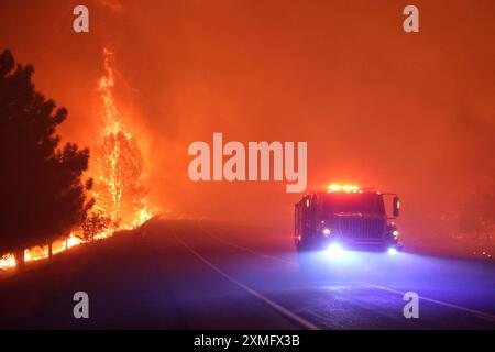 Das Foto zeigt Feuerwehrmänner, die am 26. Juli 2024 in Kalifornien, USA, gegen To Flames kämpften. Kaliforniens größtes aktives Feuer explodierte am Freitagabend, wuchs rasch unter knochentrockenen Brennstoffen an und bedrohte Tausende von Häusern, als sich die Feuerwehrleute um die Gefahr bemühten. Die Intensität und schnelle Ausbreitung des Parkfeuers veranlassten die Feuerbeamten, unwillkommene Vergleiche mit dem monströsen Lagerfeuer anzustellen, das 2018 im nahegelegenen Paradise außer Kontrolle brannte, 85 Menschen tötete und 11.000 Häuser abbrannte. Bisher wurden mehr als 130 Gebäude durch diesen Brand zerstört, und Tausende weitere sind noch immer bedroht Stockfoto