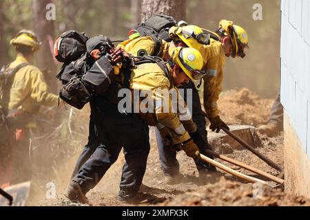 Das Foto zeigt Feuerwehrmänner, die am 26. Juli 2024 in Kalifornien, USA, gegen To Flames kämpften. Kaliforniens größtes aktives Feuer explodierte am Freitagabend, wuchs rasch unter knochentrockenen Brennstoffen an und bedrohte Tausende von Häusern, als sich die Feuerwehrleute um die Gefahr bemühten. Die Intensität und schnelle Ausbreitung des Parkfeuers veranlassten die Feuerbeamten, unwillkommene Vergleiche mit dem monströsen Lagerfeuer anzustellen, das 2018 im nahegelegenen Paradise außer Kontrolle brannte, 85 Menschen tötete und 11.000 Häuser abbrannte. Bisher wurden mehr als 130 Gebäude durch diesen Brand zerstört, und Tausende weitere sind noch immer bedroht Stockfoto