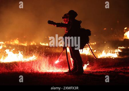 Das Foto zeigt Feuerwehrmänner, die am 26. Juli 2024 in Kalifornien, USA, gegen To Flames kämpften. Kaliforniens größtes aktives Feuer explodierte am Freitagabend, wuchs rasch unter knochentrockenen Brennstoffen an und bedrohte Tausende von Häusern, als sich die Feuerwehrleute um die Gefahr bemühten. Die Intensität und schnelle Ausbreitung des Parkfeuers veranlassten die Feuerbeamten, unwillkommene Vergleiche mit dem monströsen Lagerfeuer anzustellen, das 2018 im nahegelegenen Paradise außer Kontrolle brannte, 85 Menschen tötete und 11.000 Häuser abbrannte. Bisher wurden mehr als 130 Gebäude durch diesen Brand zerstört, und Tausende weitere sind noch immer bedroht Stockfoto